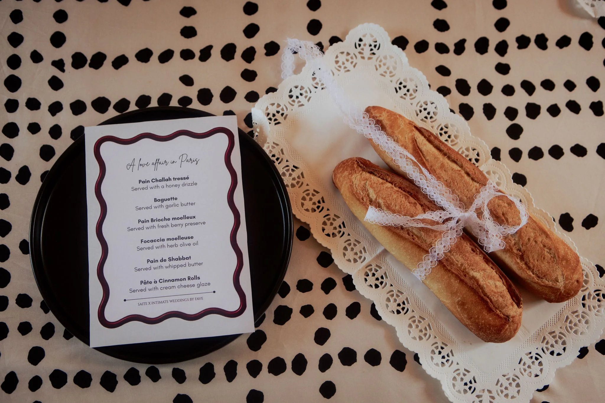 A "Love Affair in Paris" menu card beside fresh baguettes tied with lace ribbon