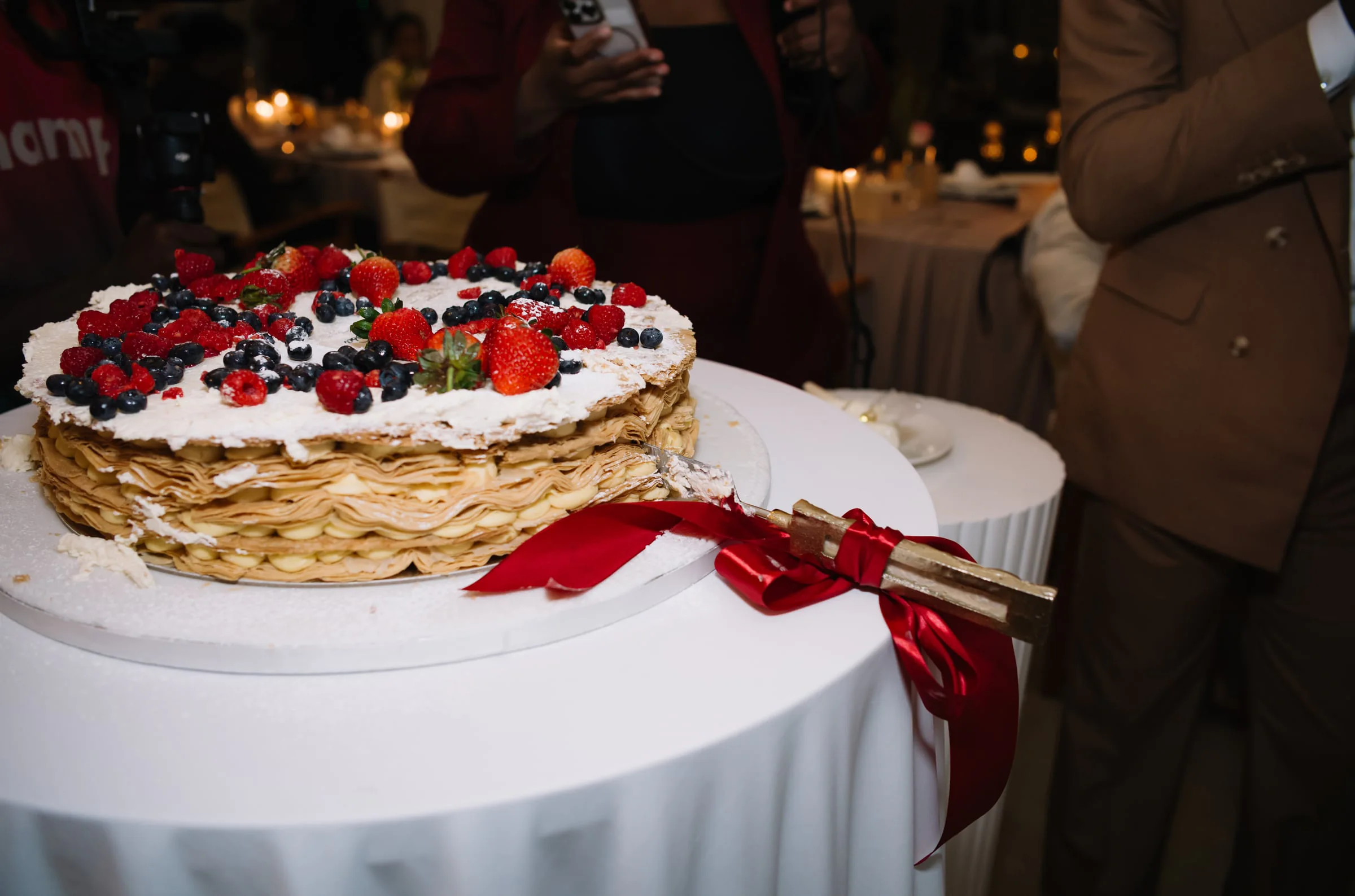 Mille-crepe wedding cake topped with fresh berries, ready to be cut