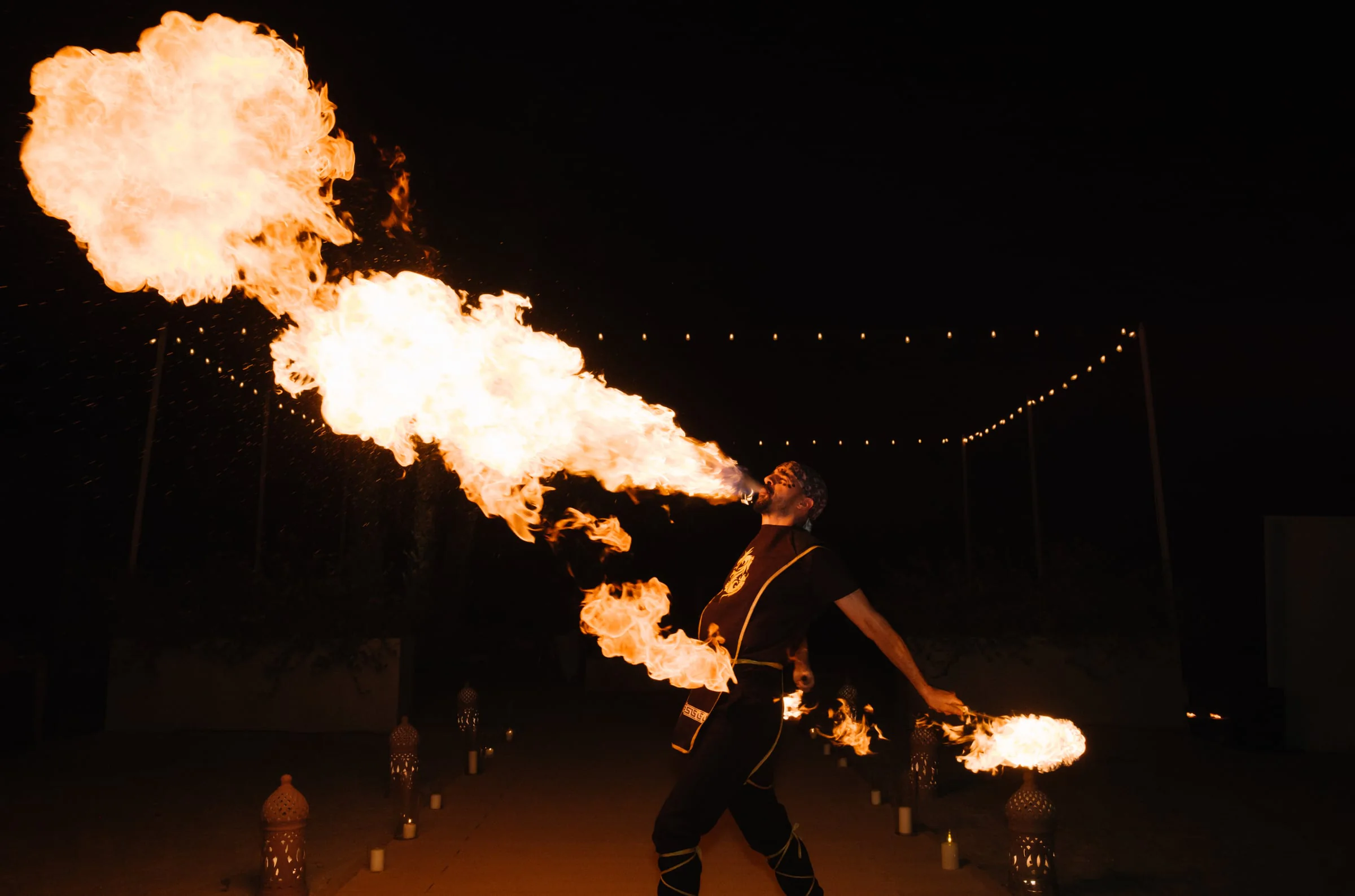 Fire performer entertaining guests under string lights at night