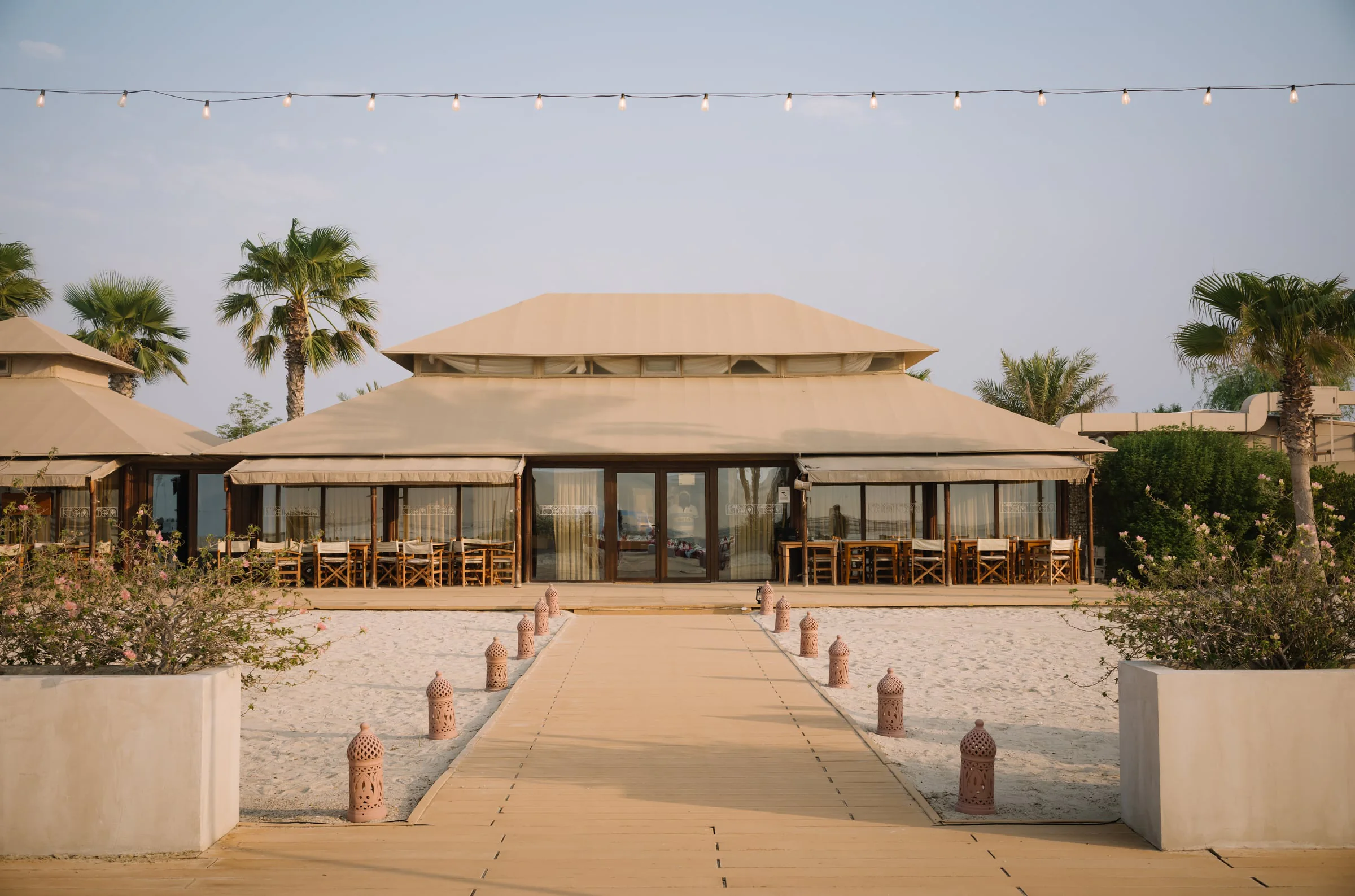 Tented desert pavilion venue framed by palm trees at golden hour