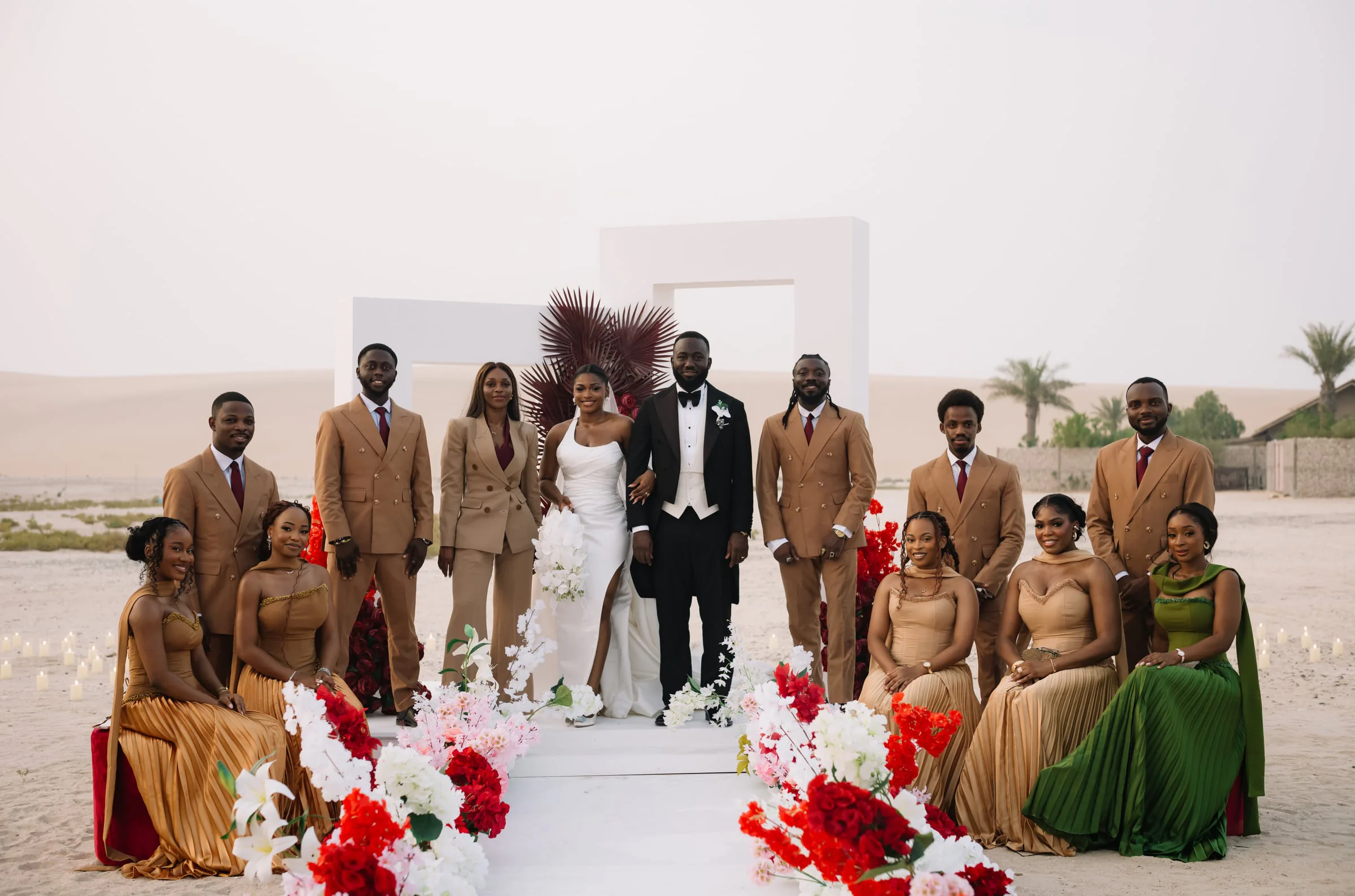 Full bridal party posed on a white platform amid the desert dunes